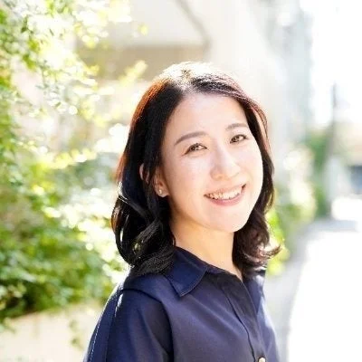 明るい屋外で笑顔を見せるアジア人女性のポートレート。