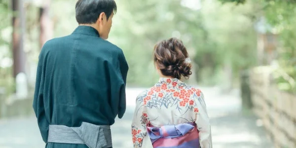 浴衣姿のカップルが、緑豊かな屋外の道を後ろ姿で歩いている様子です。夏のデートや散策を思わせる穏やかな一枚です。