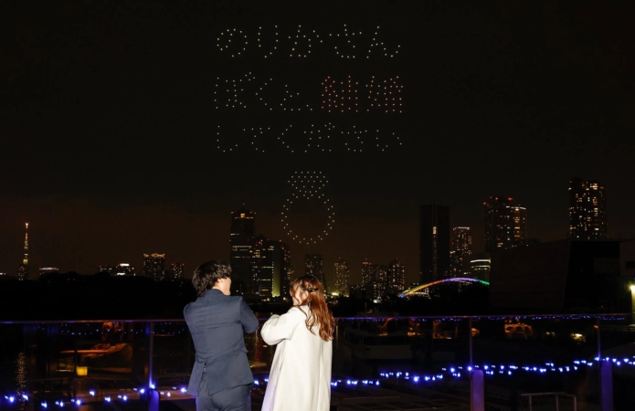 ドローンショーで「ありがとう 結婚してください」のメッセージと指輪の形が夜空に描かれる様子