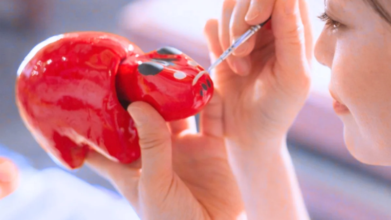 女性が赤べこに絵付けをしている様子