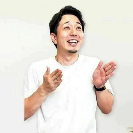 白いTシャツを着た男性が、笑顔で両手を広げて何かを見上げ、拍手をしているかのようなポーズをとっています。