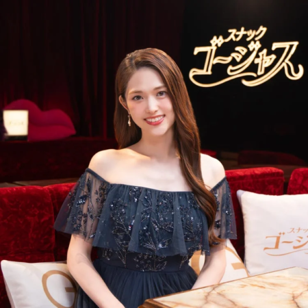 オフショルダーのネイビーのドレスを着た若い女性が、笑顔でカメラを見つめている